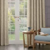 neutral floral curtains with green leaves and purple flowers at a french door. wooden armchair with blue cushions with matching wooden side table