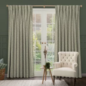 sage green floral curtains at a set of french doors with a white armchair and wooden table