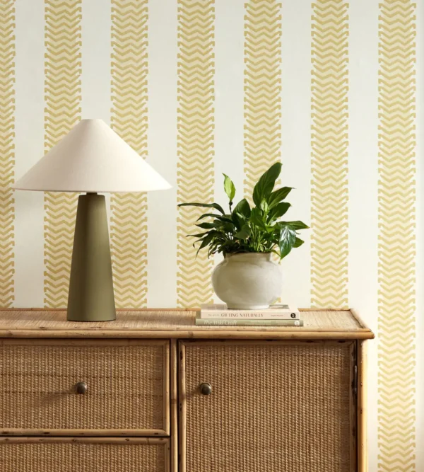 Bradgate Wallpaper - Honey by yellow striped wallpaper and wall with cabinets and vases