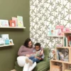 white botanical wallpaper and wall with armchair and toys