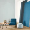 blue plain wallpaper and wall with armchair and pouf