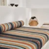 orange striped bed with cushion and vases