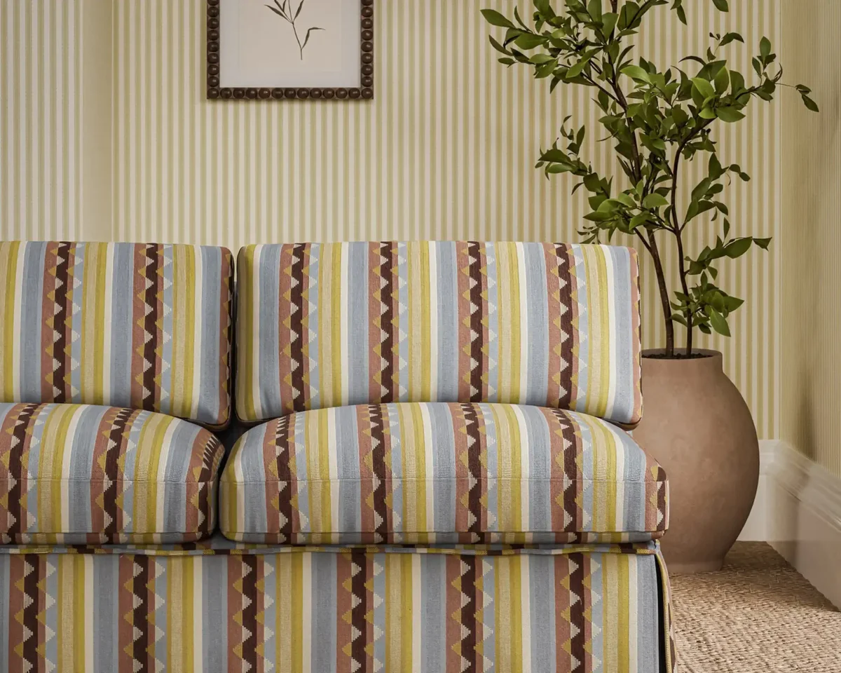 Lutley Stripe Fabric - Damson / Medlar by red striped sofa with plants