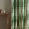 green striped curtain with side table and vases